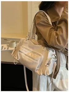 Gedetailleerd overzicht van dames retro beige lederen schoudertas met meerdere zakken en ritsen.