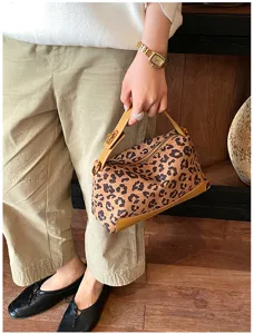 Detailopname van trendy panterprint handtas met bruine lederen handgreep en rits.
