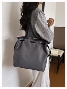Detailansicht der grauen Nylon Kordelzug Tasche auf der Schulter, ideal für das Pendeln.