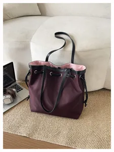 Detailaufnahme der weinroten Nylon-Tragetasche mit schwarzen Trägern für das Pendeln.