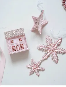 Detailed close-up view of pink glitter Christmas hanging ornaments featuring cute house and stars.