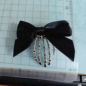Halloween gothic black bow hairpin with silver skeleton hand claw clip for dark style hair.