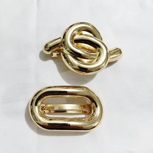 Elegante set di fermagli per capelli in metallo dorato, nodo e design geometrico ovale.