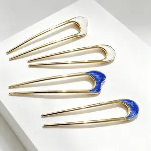 Vue détaillée d'épingles à cheveux dorées en U avec de beaux détails émaillés bleus et blancs.