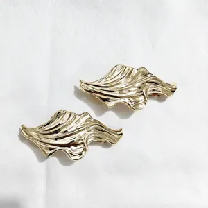 Gold metal hair clip detail, abstract wave geometric design, elegant retro styling accessory for women.