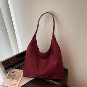 Detailopname van de vintage bordeauxrode suède schoudertas met zachte textuur en ruim ontworpen.
