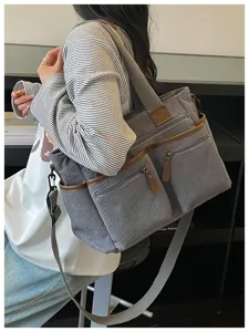 Casual grijze corduroy tote tas met meerdere vakken, bruine afwerking en verstelbare schouderriem.