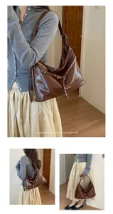 Brown patent leather shoulder bag detail, stylish hobo bag with metallic grommets and straps.