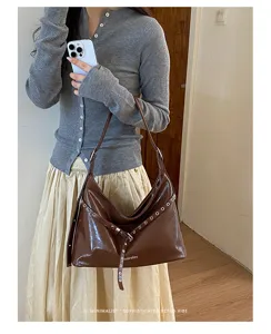Detail view of a retro brown PU leather shoulder bag featuring stylish metal grommet straps.