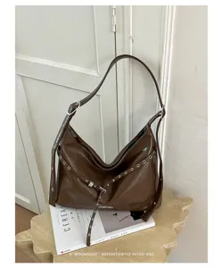 Brown patent leather shoulder bag with grommet straps, chic retro motorcycle style purse.