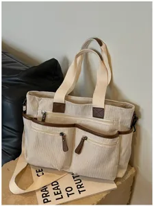 Detail van beige corduroy multi-zak tote tas met bruine lederen afwerking en metalen ritsen.