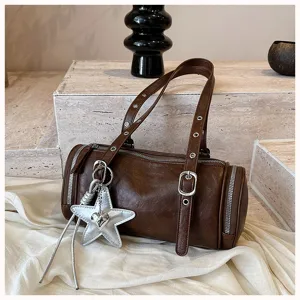 Braune zylindrische Leder-Umhängetasche Detail mit silbernem Sternanhänger und Ösenriemen.