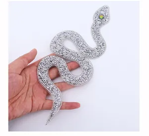 Close-up of silver snake rhinestone patch sparkling crystal DIY clothing bag decor.