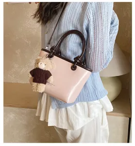 Stylish pink women handbag with cute bear pendant, trendy color-matching shoulder bag for daily use.