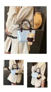 Chic light blue tote bag with brown handles and cute bear pendant for women daily fashion.