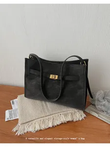 Vista dettagliata di una borsa tote nera vintage in pelle con serratura dorata e spallacci.