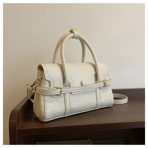 Elegante crèmekleurige lederen handtas voor dames, vintage schoudertas met chique metalen gespen.