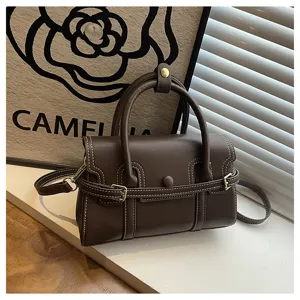 Gedetailleerd overzicht van donkerbruine vintage damestas met contrasterende stiksels en hardware.