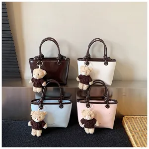 Detail view of fashionable colorful small handbags with cute plush bear pendant.