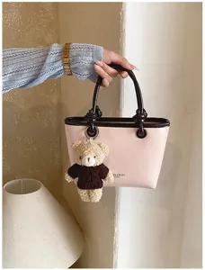 Cute pink handbag detail with contrast brown handle and lovely fluffy bear plush pendant.