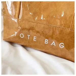 Detailaufnahme der wasserdichten Tasche, braunes Material mit PVC-Schicht und weißem Textdruck.