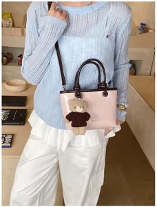 Stylish pink shoulder bag with brown handles and cute bear pendant for women chic daily wear.