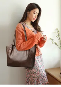 Detailopname van een stijlvolle bruine PU lederen shopper tas gedragen door een model.