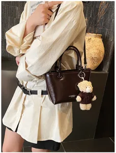 Korean style dark brown tote bag detail showing cute teddy bear pendant and premium glossy texture.