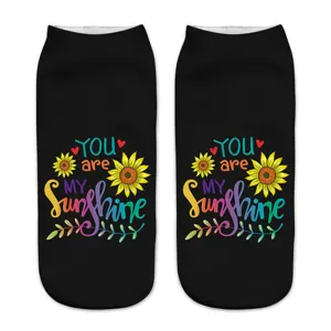 Close-up detail of black ankle socks featuring vibrant sunflower and motivational print.