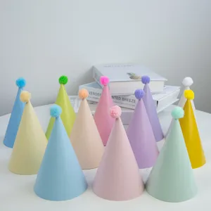 Bunte Papier-Geburtstagshüte mit flauschigen Pompons, verschiedene Farben für Partydekorationen.