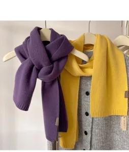 Detailed view of soft winter knit wool scarves in purple and yellow hanging on display.