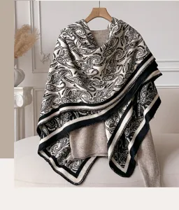 Detailed view of a black and white paisley patterned shawl draped on a knitted sweater.