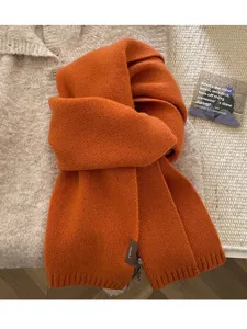 Orange knitted winter scarf detail view, soft cozy wool texture for cold weather fashion.