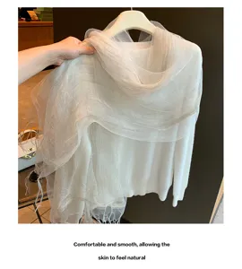 Detailaufnahme des transparenten Netzschals und weißen Strickoberteils, weiche Textur.