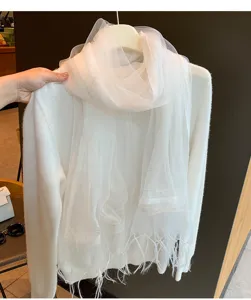 Detailansicht des eleganten, leichten doppelten weißen Tüllschals auf dem Strickpullover.
