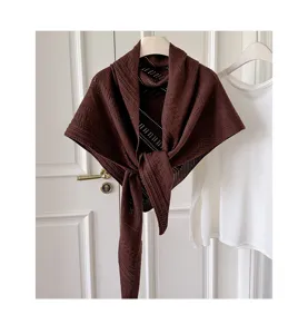 Nahaufnahme des braunen Strick-Dreieckscharfs mit feiner Lochmuster-Textur und Fall.