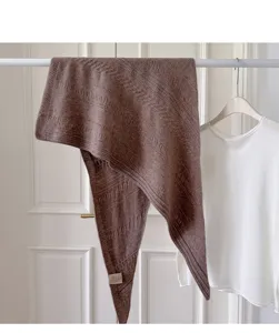 Detailansicht eines braunen Wollmisch-Strick-Dreiecktuchs an einer Stange für Herbst und Winter.