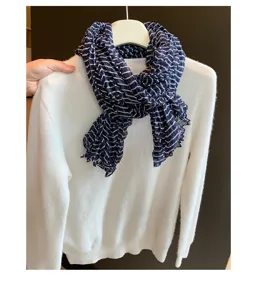 Detailansicht des dunkelblauen, gestreiften Plisséeschals auf Pullover, leicht und elegant.