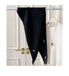 Detailaufnahme des schwarzen Strick-Dreiecktuchs mit strukturierter Stoff und Metall-Label.