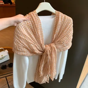 Modischer brauner karierter Plissierschal kombiniert mit weißem Strickpullover für Damen.