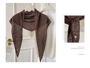 Detailaufnahme des braunen Strick-Dreiecksduchs mit leichtem Stoff und Metallanhänger.