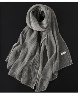 Nahaufnahme des grauen Schals mit Knittertextur, weich drapiert und im eleganten Retro-Stil.