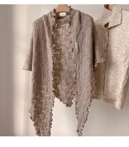 Detalle de chal triangular de punto con borde ondulado suave para mujer en otoño e invierno.