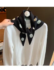 Vue rapprochée du foulard triangulaire en tricot à pois noirs et verts montrant les détails.