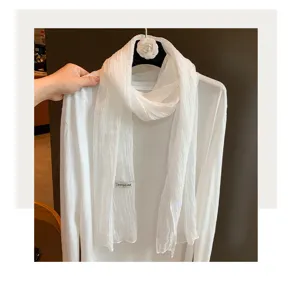 Nahaufnahme eines weissen knitterigen Schals, leichtes transparentes Gewebe fuer Styling.