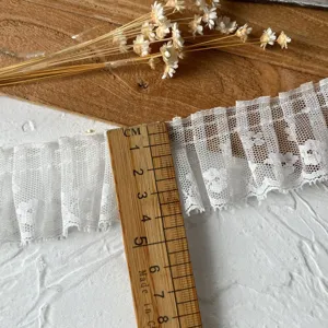 White pleated lace trim detail shot showing width with wooden ruler, perfect for DIY craft.