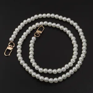 Gros plan sur le détail de la chaîne en perles blanches avec fermoir mousqueton doré.