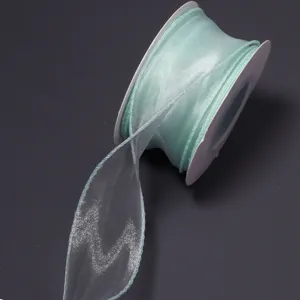 Detail view of light green organza ribbon roll with translucent fishtail yarn texture for DIY.