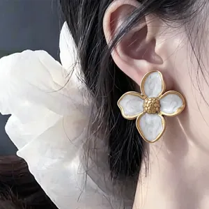 Exquisite stainless steel four-petal flower stud earrings with retro gold edge and white enamel.