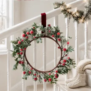 Corona de Navidad con bayas rojas escarchadas y hojas verdes, ideal para decoración navideña.